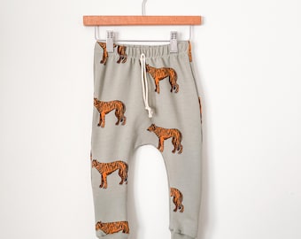 May include: A pair of light green sweatpants with a tiger print. The sweatpants have a drawstring waist and elastic cuffs.