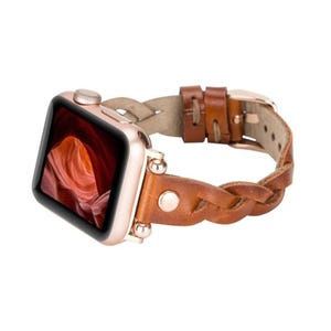 May include: A brown leather braided Apple Watch band with rose gold hardware. The band is designed for the Apple Watch Series 4 and later.