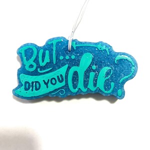 Puede incluir: Un ambientador de coche azul con el texto "But... did you die?" en letras verdes.