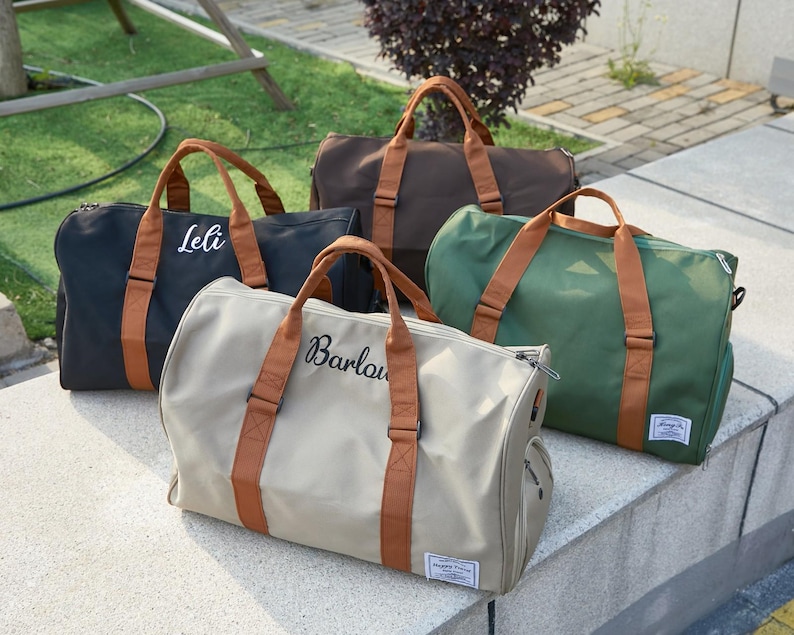 Peut inclure: Quatre sacs de sport en noir, marron, vert et beige, chacun dot&eacute; de poign&eacute;es et de sangles en tissu marron. Le sac noir porte le nom Leli et le sac beige porte le nom Barlow, inscrits respectivement en texte cursif blanc et noir.