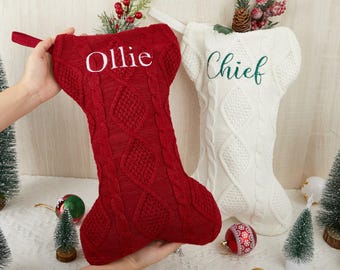 May include: Two cable-knit Christmas stockings, one deep red with the white embroidered name Ollie and one cream white with the dark green embroidered name Chief. Both stockings feature a textured diamond and vertical cable pattern throughout.
