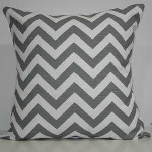 May include: Square cushion featuring a grey and white chevron pattern. The cushion has a textured finish and is designed for home decor. The zig-zag design adds a modern touch to any living space.