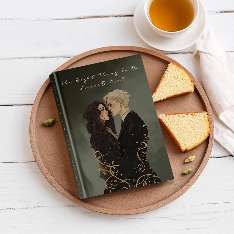 May include: A hardcover book titled "The Right Thing To Do" with the subtitle "LovesBites8" featuring an illustration of two people embracing. The book is on a wooden tray with slices of cake and a cup of tea.
