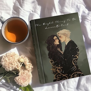 May include: A book titled "The Right Thing To Do" with a romantic illustration of two people. A cup of tea and a bouquet of flowers are next to the book on a white surface. The book cover is dark green with gold accents.
