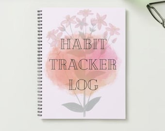 May include: A pink and white spiral bound notebook with a watercolor background and floral design. The text "HABIT TRACKER LOG" is printed in black on the front cover.