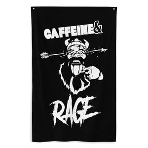 May include: Black wall tapestry with a white graphic of a Viking-like figure drinking coffee, an arrow through the head, and the words "CAFFEINE & RAGE". The design is bold and eye-catching.