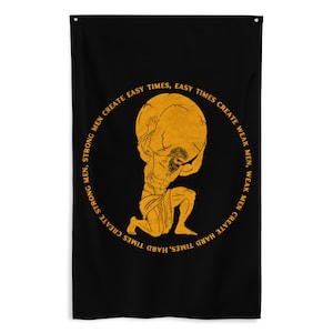 May include: Black wall flag featuring a gold illustration of Atlas carrying a golden globe. The text around the globe reads: "Strong men create hard times, hard times create weak men, weak men create easy times, easy times create strong men."
