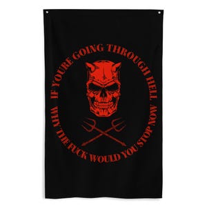 May include: Black flag featuring a red devil skull with horns and crossed pitchforks. The text around the skull reads, "WHY IF YOU'RE GOING THROUGH HELL NOW WHY THE FUCK WOULD YOU STOP".