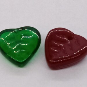 May include: Two heart-shaped glass beads, one green and one burgundy.