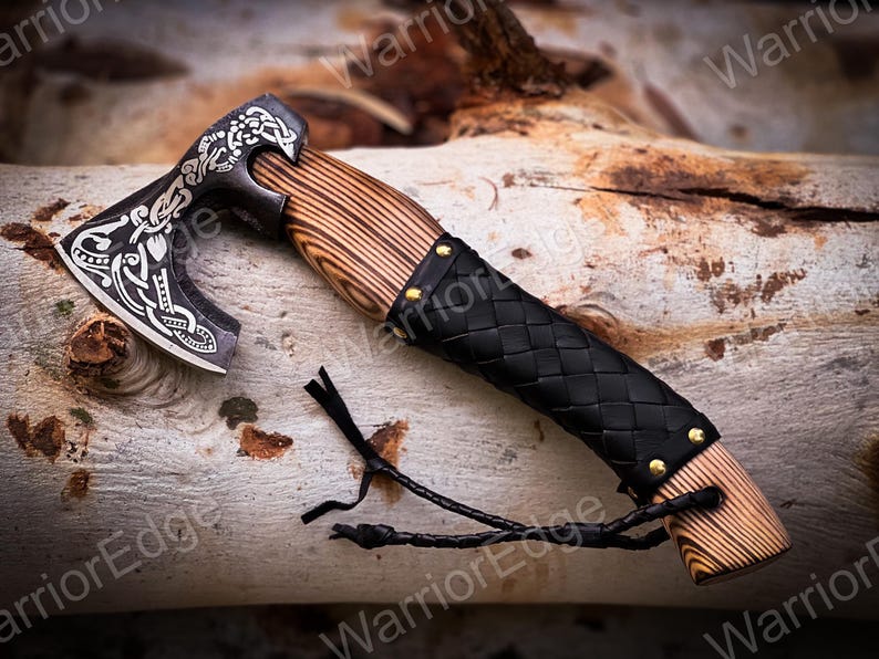 May include: A black and silver axe with a wooden handle wrapped in black leather. The axe has a decorative design on the blade and a leather strap attached to the handle.