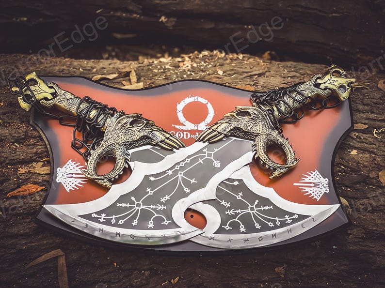 May include: A pair of silver-colored axes with black and white designs, mounted on a red and black shield with the words "God of War" and a symbol.