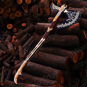 May include: A decorative axe with a black blade and gold accents. The axe has a wooden handle and a curved blade with intricate designs. The axe is resting on a pile of logs.