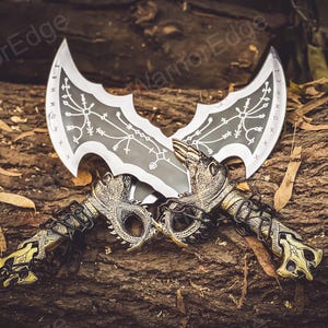 May include: Two silver and black fantasy swords with intricate designs on the blades. The swords are crossed and have gold-colored dragon-like handles.