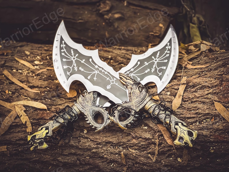 May include: Two silver and black fantasy swords with intricate designs on the blades. The swords are crossed and have gold-colored dragon-like handles.