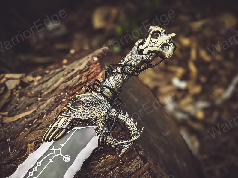 May include: A decorative sword with a gold and silver finish. The sword has a dragon-like handle with intricate details and a black blade with a design.