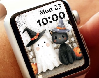 May include: White smartwatch displaying a Halloween-themed graphic. The screen shows a ghost and a black cat wearing witch hats, with pumpkins and the date "Mon 23 10:00". The watch is on a wrist.