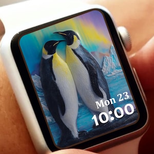 May include: A white smartwatch with a screen displaying two penguins in a colorful arctic scene. The watch face shows the date, Monday the 23rd, and the time, 10:00. The watch has a white band and a silver-colored button.