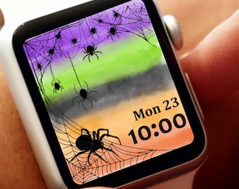 May include: A white smartwatch with a Halloween-themed watch face. The watch face features a watercolor design with purple, green, gray, and orange stripes, spiderwebs, and black spiders. The date and time, "Mon 23 10:00", are displayed in the bottom right corner.