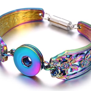 May include: A rainbow iridescent metal bracelet with a snap closure and floral design.