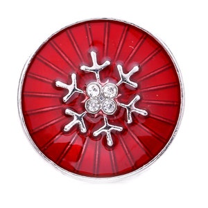 May include: Red round button with a silver snowflake design and clear rhinestones. The snowflake is centered on the button and has a red background with silver lines radiating from the center.