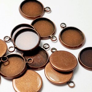 May include: A group of 12 copper-colored round metal pendant trays with a clear glass insert. The trays have a loop on the top for hanging.