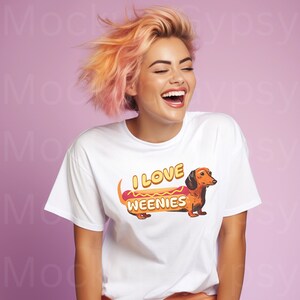 May include: A white t-shirt featuring a cartoon dachshund dressed as a hot dog. The text on the shirt reads "I love weenies".