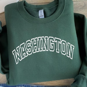May include: Forest green sweatshirt with white text that reads "WASHINGTON" in an arched font.