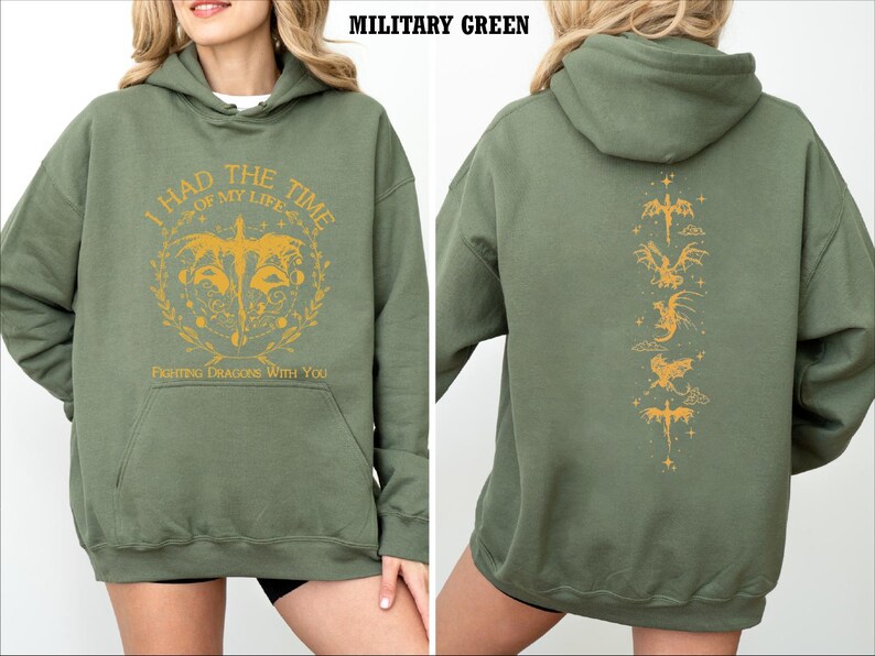 Puede incluir: Una sudadera con capucha verde con un estampado gr&aacute;fico amarillo en la parte delantera que dice "Tuve el mejor momento de mi vida. Luchando contra dragones contigo." La parte posterior de la sudadera tiene una l&iacute;nea vertical de siluetas de dragones amarillos.