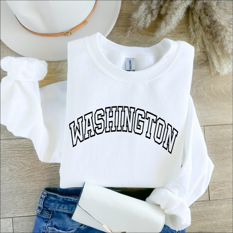 May include: White sweatshirt with black text that reads "WASHINGTON" in an arched font.