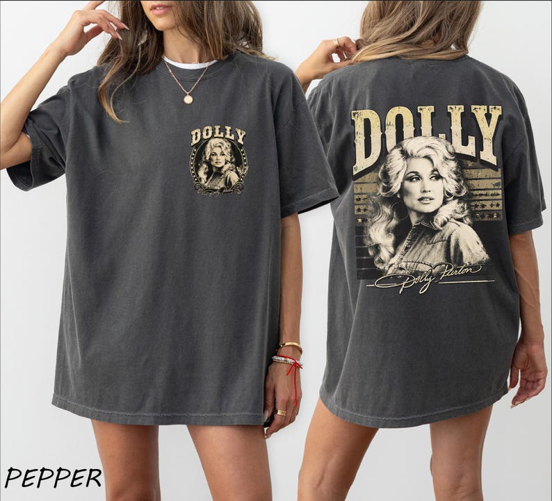 A woman wearing a gray t-shirt with a graphic design featuring a portrait of Dolly on the back.
