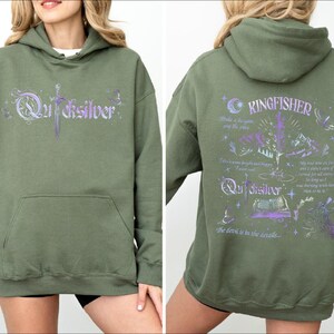 a woman wearing a green sweatshirt with purple writing on it