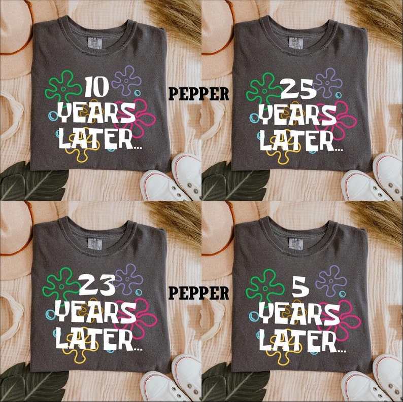 May include: Four gray t-shirts with a white graphic of a cartoon character. Each shirt has a different number on it: 10, 25, 23, and 5. The text below the numbers says "Years Later..."