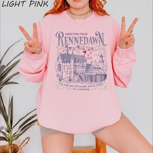 a woman wearing a pink shirt with a picture of a castle on it