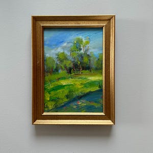 Peut inclure: Peinture &agrave; l'huile encadr&eacute;e d'or repr&eacute;sentant un paysage verdoyant. Le tableau montre un champ vert, des arbres et un ciel bleu nuageux. Une petite &oelig;uvre d'art encadr&eacute;e, de style impressionniste.