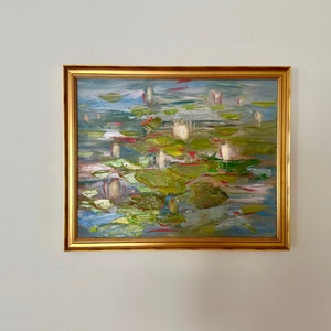 Könnte beinhalten: Ein gerahmtes Gemälde eines Teichs mit weißen Seerosen und grünen Seerosenblättern. Das Gemälde ist in einem lockeren, impressionistischen Stil mit sichtbaren Pinselstrichen ausgeführt. Der Rahmen ist golden.