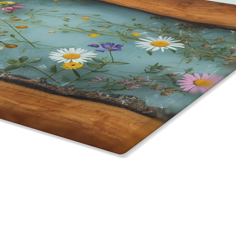 Puede incluir: Una tabla de servir rectangular de madera con un centro de resina azul claro, adornada con flores y vegetaci&oacute;n coloridas. La tabla presenta un borde de veta de madera natural, creando una est&eacute;tica r&uacute;stica y elegante. Perfecta para servir aperitivos o exhibir objetos decorativos.