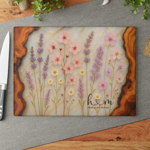 Könnte beinhalten: Rechteckiges Schneidebrett mit floralem Design mit rosa, lila und weißen Blumen. Das Brett hat einen hellen Hintergrund mit einem Holzmaserungsrand und dem Text "h♡m" mit den Namen "Heather and Michael".