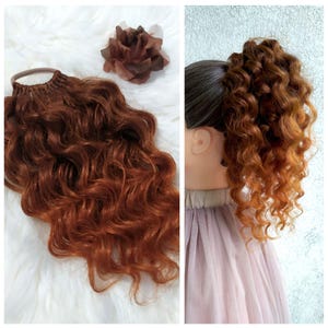 Può includere: Un'estensione per capelli lunga, riccia, color castano rossiccio con un elastico per capelli marrone. L'estensione è mostrata su una superficie bianca e su un manichino con un vestito lilla chiaro.