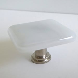 May include: White square glass cabinet knob with a brushed nickel base.