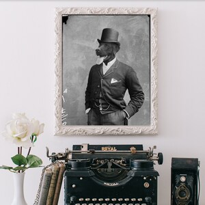 May include: A black and white photo of a dog wearing a top hat and suit, framed in a white frame, hanging on a white wall. A vintage typewriter, a camera, and a vase of white roses are on a white table in front of the photo.