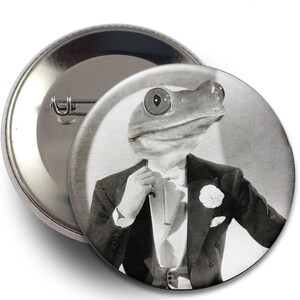 May include: A black and white button featuring a frog wearing a tuxedo and a boutonniere.