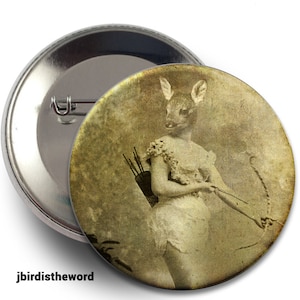 May include: A vintage-style button featuring a woman with a deer head and a bow and arrow. The image is in sepia tones and has a faded, antique look.