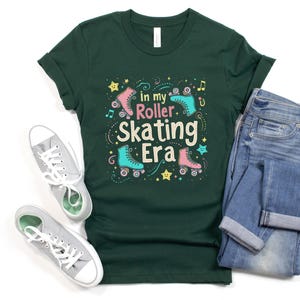 May include: A dark green t-shirt with a graphic design of roller skates and the text "In my roller skating era".