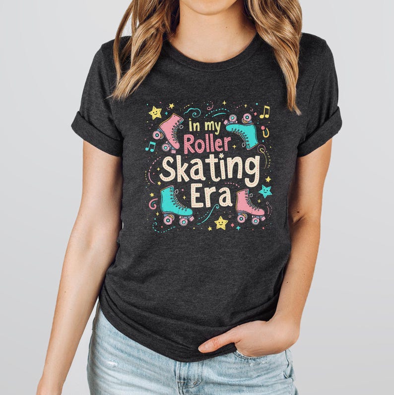 May include: A dark heather grey t-shirt with a graphic design featuring roller skates, stars, and music notes. The text on the shirt reads "In my Roller Skating Era".