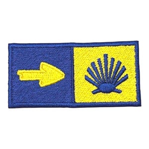 May include: Embroidered patch featuring a blue and yellow design. The left side has a yellow arrow on a blue background. The right side has a yellow background with a blue shell design. The patch is rectangular.