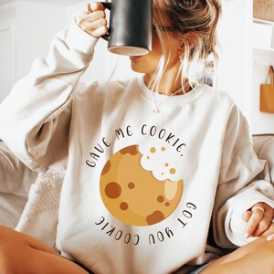 May include: A white sweatshirt with a brown cookie graphic and the text "Gave me cookie. Got you cookie."
