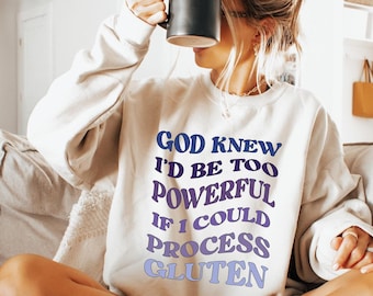 May include: A white sweatshirt with a purple and blue graphic print that says "God knew I'd be too powerful if I could process gluten".