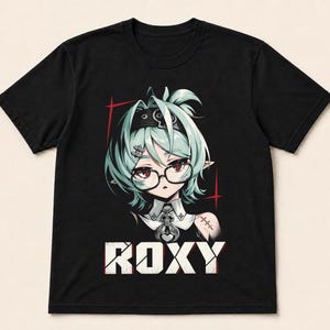 May include: A black short-sleeved t-shirt featuring a graphic print of an anime-style character with mint green hair, glasses, and a skull-themed collar. The character is positioned above the white text ROXY, which is displayed in a bold, blocky font.
