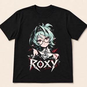 May include: A black short-sleeve t-shirt featuring a graphic print of an anime-style character with mint green hair, glasses, and a dark outfit. The character is positioned above the text ROXY in a stylized, sharp white font with red accents.