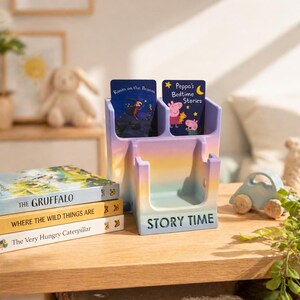 May include: A multi-coloured story time organiser with the words "STORY TIME" on the front. It holds two children's books and sits next to a stack of books including "The Gruffalo". A wooden toy car is also visible.